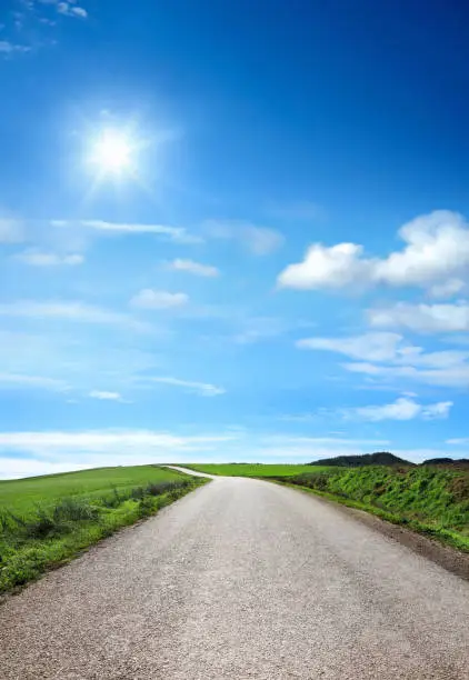 close up countryside empty road over sunny blue sky and shinning sun
