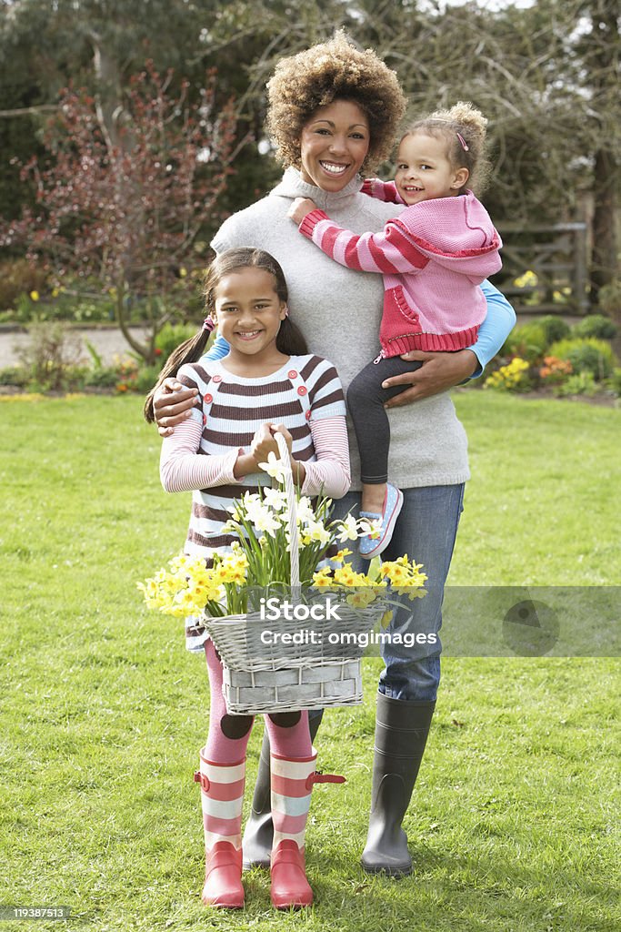 Mãe e crianças segurando Cesta de narcisos no jardim - Foto de stock de 30 Anos royalty-free