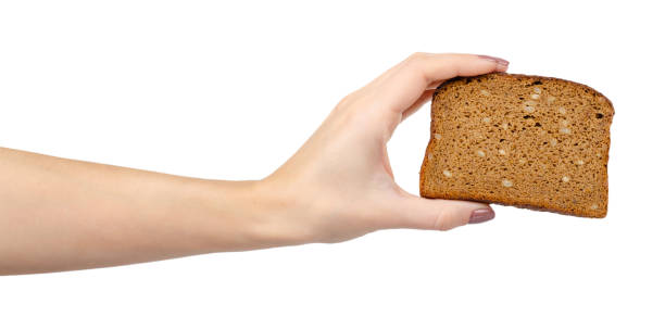 Brown bread with seeds, heathy food. Isolated on white. Hand with slice of brown bread with seeds, heathy food. Isolated on white background. heathy stock pictures, royalty-free photos & images