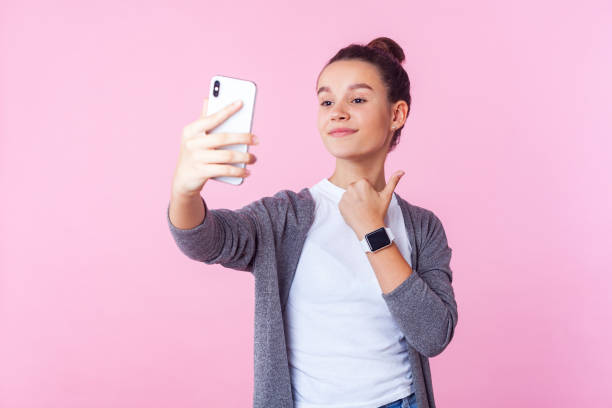 jak! portret pozytywnej nastoletniej dziewczyny uśmiecha się i pokazuje kciuki w górę podczas nawiązywania połączeń wideo. odizolowane, różowe tło - telephone child isolated on white elegance zdjęcia i obrazy z banku zdjęć