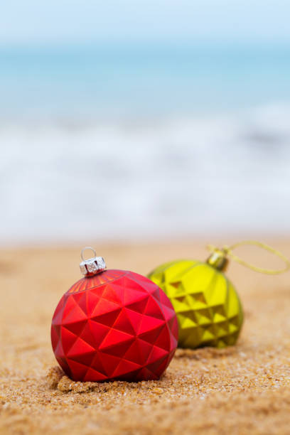 istock two Christmas ball on the sandy shore 1193882206