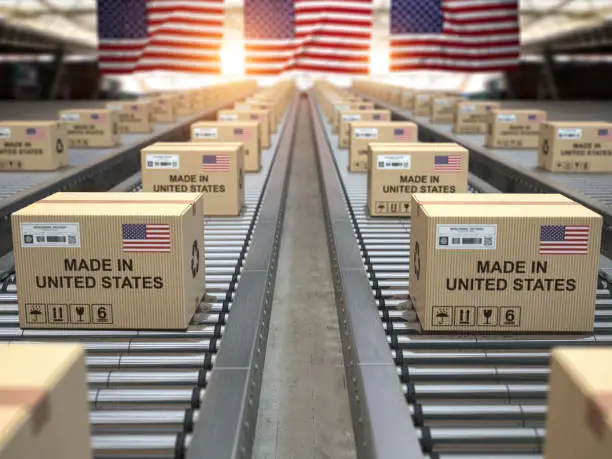 Photo of Made in USA United States. Cardboard boxes with text made in USA and american flag on the roller conveyor.