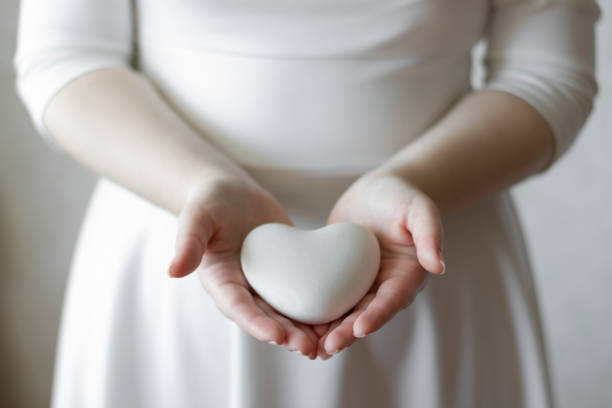 istock Women's hands are holding a small white plaster heart. 1193899464