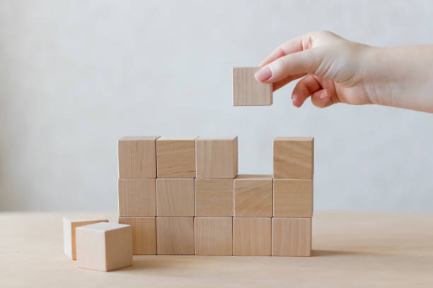 istock Hand holds wooden blocks placing them into a structure. 1193899467