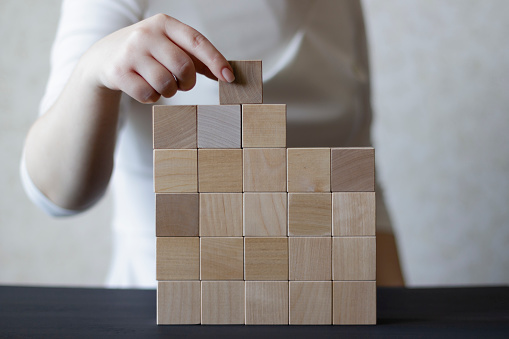 Woman's hand stacking wooden blocks. Business development concept.