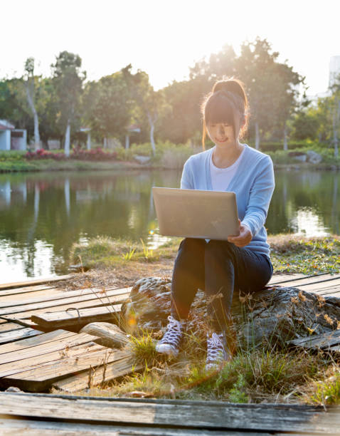 istock Woman using laptop by the lake 1193902757