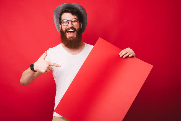 istock Excited bearded guy in glasses, pointing at  empty blank, standing over red background 1193903053