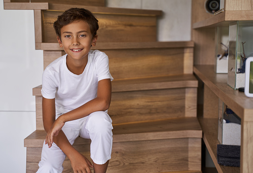 Happy kid looking on camera while being on stairs stock photo