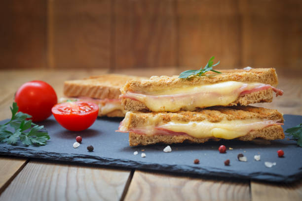 Toasted sandwiches with salami and melted cheese on wooden background. stock photo