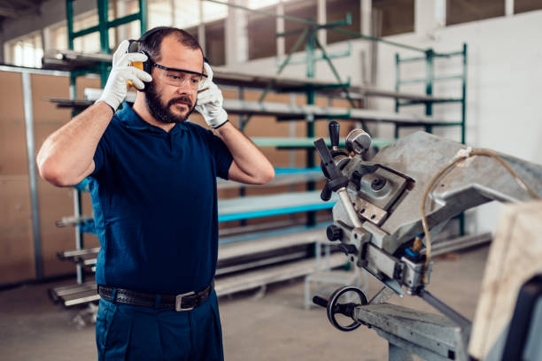 istock Band saw cutting machine worker putting on protective earmuffs 1193906769