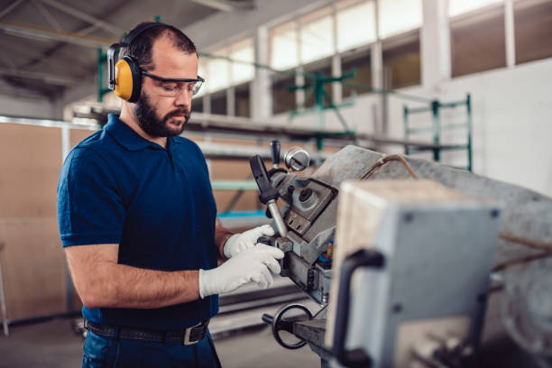 istock Factory worker operating band saw cutting machine 1193907046