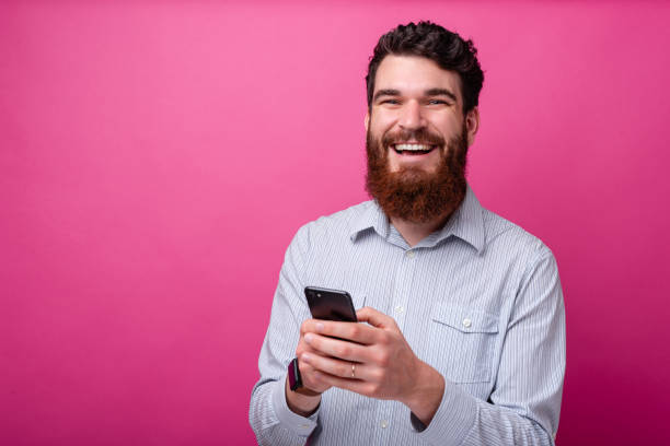 istock Cheerful bearded man looking at the camera and typing something on his phone. 1193907807