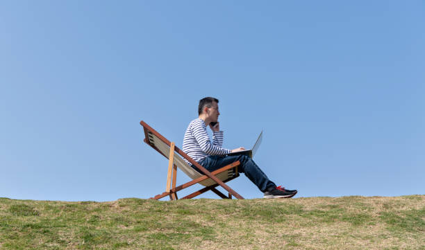 istock Man sitting on deck chair and using phone 1193908279