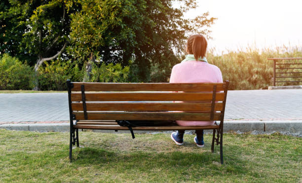 istock Woman sitting on park bench 1193909112