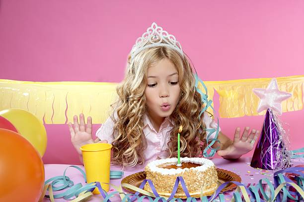 pequena menina loira feliz soprando velas de aniversário festa com bolo - streamer ribbon curly hair party - fotografias e filmes do acervo