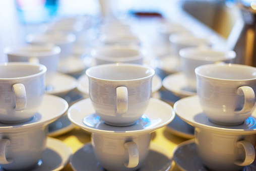 Coffee or tea ceramic cup stacked on buffet table that ready to serve to participant / attendees in seminar or cafe