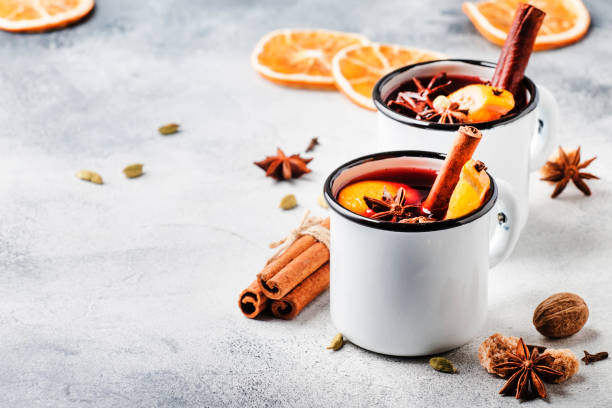 Mulled wine in white metal mugs with cinnamon, spices and orange on concrete background, traditional drink on winter holiday. Copy space for text Mulled wine in white metal mugs with cinnamon, spices and orange on concrete background, traditional drink on winter holiday. Copy space for text mulled wine photos stock pictures, royalty-free photos & images