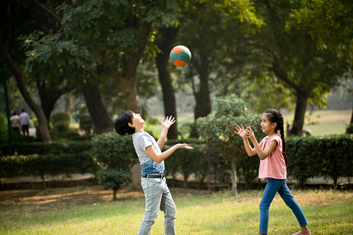 Side view of boy kicking a football in the meadow on a sunny day.