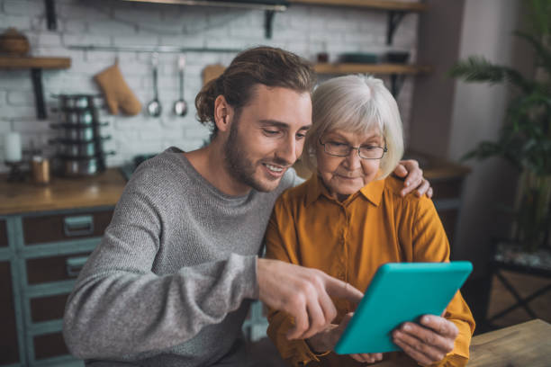 istock Young handsome man in grey shirt and his mom searfing internet 1193919082