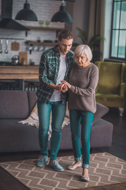 istock Young man in jeans helping his mom to walk 1193919111