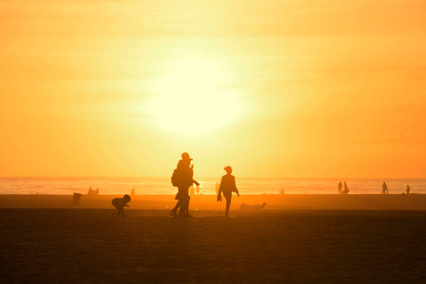 Silhouette background image of people enjoy people walking on the beach in colorful sunset over sky, Santa Monica California, USA.