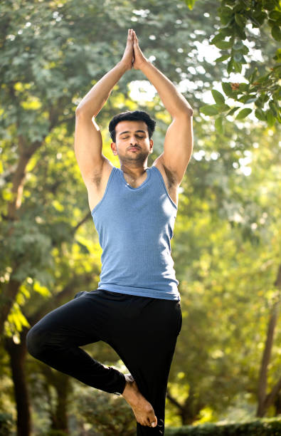 公園でヨガのポーズを練習している男性 - tree pose ストックフォトと画像