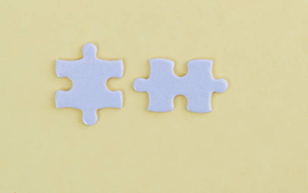 istock Two white jigsaw pieces on yellow background 1193925698