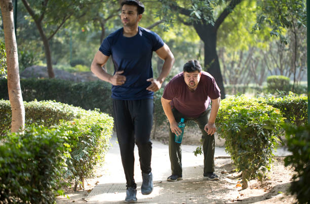 istock Fitness instructor jogging while exhausted fat man is taking a break at park 1193925748