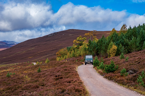 Landrover Defender, Cairngorms National Park , Scotland, UK - October 12, 2019: legendary Landrover driving on narrow dirt road