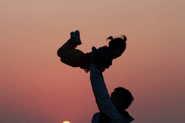 silhouette of father and daughter silhouette of father and daughter under sunset. background for father's day and happy family. baby gun stock pictures, royalty-free photos & images