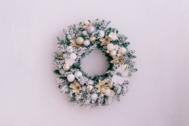 istock Snowy christmas wreath on a white wall with place for text, close up 1193929334