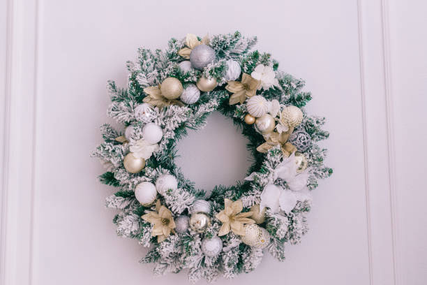 istock Snowy christmas wreath on a white wall with place for text, close up 1193929335
