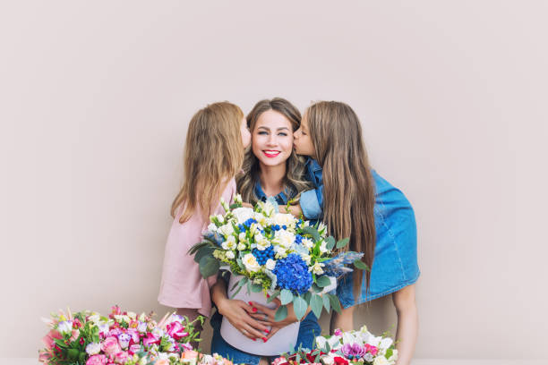 mère heureuse de famille et deux belles filles filles filles en vacances dans des fleurs ensemble sur le fond d'isolement - mothers day flower gift bouquet photos et images de collection