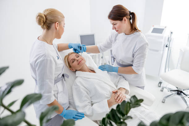 Specialists standing near smiling adult woman in beauty salon stock photo Specialists standing near smiling adult woman in beauty salon stock photo