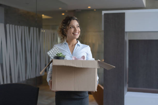 Business woman moving into a new office Happy business woman moving into a new office and carrying her belongings in a box office leave stock pictures, royalty-free photos & images
