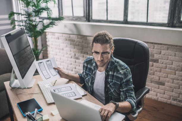 istock Young man in eyeglasses sitting at the desk 1193930324