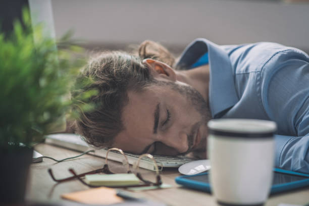 istock Young bearded man in blue shirt having a nap at work 1193930436
