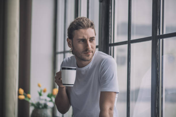 istock Romantic long-haired man drinking his morning coffee near the window 1193930465