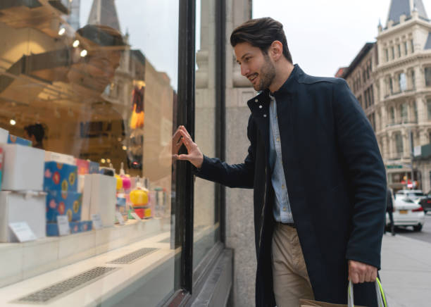 mann auf der straße mit blick auf ein schaufenster - garment stock-fotos und bilder