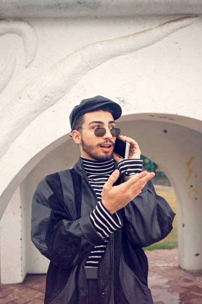 istock Young handsome man in leather jacket talking on mobile phone outdoors. 1193939102