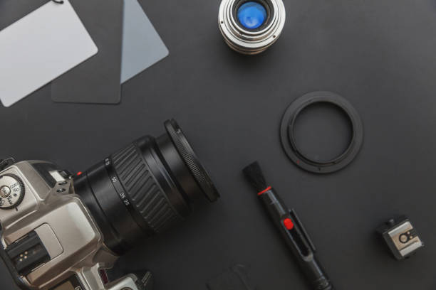 istock Photographer workplace with dslr camera system, camera cleaning kit, lens and camera accessory on dark black table background. Hobby travel photography concept Flat lay top view copy space 1193945821