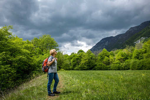 Senior woman walking on the path along the Soca River in Triglav National Park in Slovenia, Europe. Some parts of the trail move away from the river. Nikon D850.