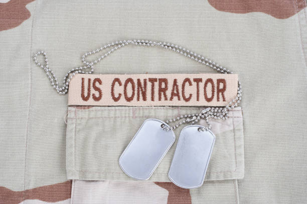 istock US CONTRACTOR branch tape with dog tags patch on desert camouflage uniform 1193956101