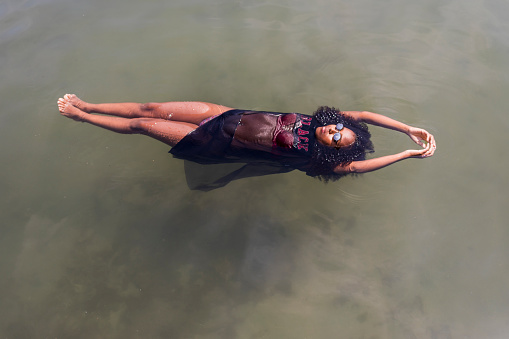 Beautiful young Afro woman floating at a pool of water