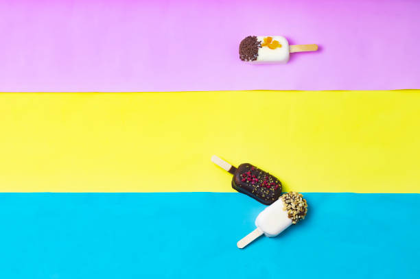 Composition Chocolate popsicle ice cream stick on yellow, lemon and pink blue background, pastel color. Place for text, copy space banner. View from above. Ice cream as cars crashed into each other