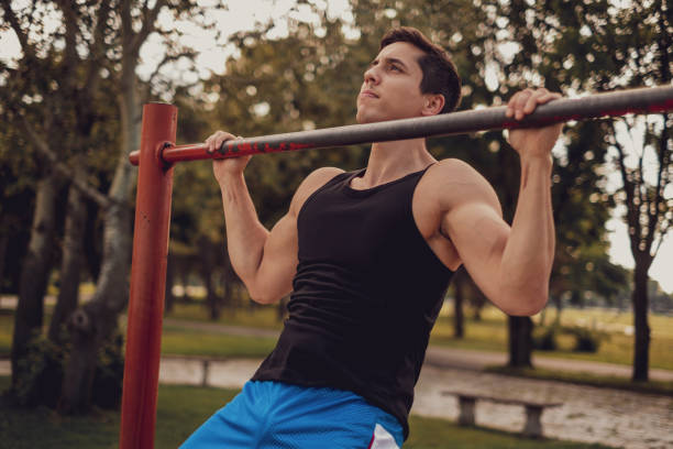 istock Man doing chin ups on the bar in the park 1193964314