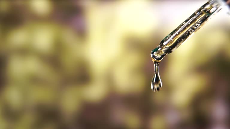 Slow motion liquid drops are falling from the pipette into bottle