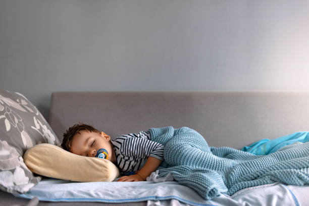 Sleeping beauty Adorable little child boy sleeping in the bed facing the camera. young hot stock pictures, royalty-free photos & images