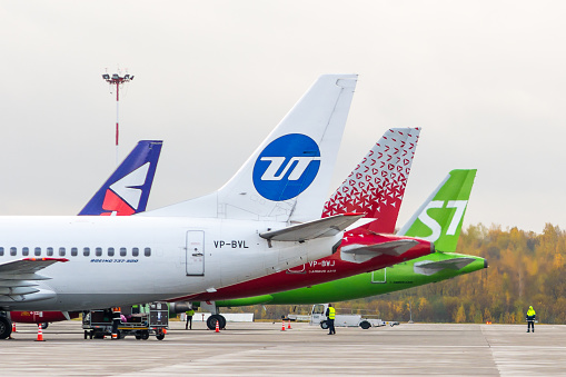 Tails of Airplanes on stands.  UTair Boeing 737-500, VP-BVL. Rossiya Airlines Airbus A319, VP-BWJ. Pulkovo International Airport, Saint-Petersburg, Russia. 13 October 2019.