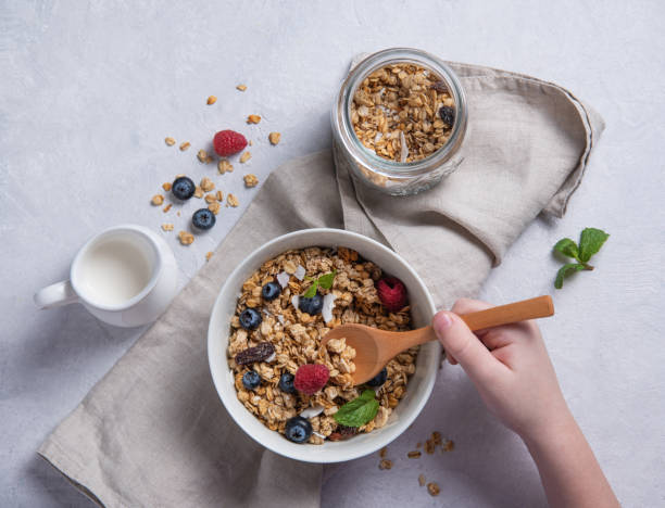 muesli dolce con bacche in piatto con latte di cocco su tavolo grigio. - oatmeal raisin porridge nut foto e immagini stock